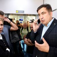 Former Georgian President Mikhail Saakashvili talks on a smartphone while standing next to ex-Ukrainian Prime Minister Yulia Tymoshenko at the railway station in Przemysl, Poland, on Sunday. Former Georgian leader Saakashvili's train halted near Ukraine border