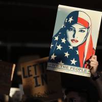 A protester holds a sign at San Francisco International Airport during a January demonstration to denounce President Donald Trump’s executive order that bars citizens of seven predominantly Muslim-majority countries from entering the U.S. The Trump administration announced new restrictions after spending months hashing out the details determined to avoid a repeat of the chaos of Trump’s first travel ban. Trump travel ban seen on more solid ground as top court drops hearing but critics say Muslims still target