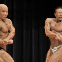 Naoki Go (right) strikes a pose during the Japan Open bodybuilding competition on Aug. 27 in Kawasaki alongside men’s winner Seiichiro Kimura. As more Japanese take up bodybuilding, a veteran chases a championship