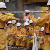 Staff from the U.S. Embassy practice using ropes for rescue operations during an annual disaster drill Friday at the Roppongi Hills complex in Minato Ward, Tokyo. Missiles join quakes, typhoons in annual disaster drills