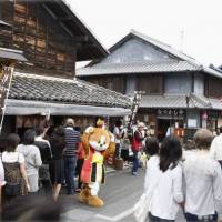 Tourists walk by traditional wooden houses in Inuyama, Aichi Prefecture. The government plans to take measures to promote the use of historic buildings as restaurants or lodging facilities to attract tourists. Tourism ministry wants to convert historic Japanese buildings into tourist draws