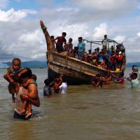 Smoke is seen on Myanmar’s side of border as Rohingya refugees leave a boat after crossing the Bangladesh-Myanmar border in Shah Porir Dwip, Bangladesh, on Sept. 11. Unwavering support for Suu Kyi needed