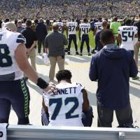 The Seahawks’ Michael Bennett sits during the playing of the U.S. national anthem as teammate Justin Britt places a hand on his shoulder before their game against the Green Bay Packers on Sunday afternoon in Green Bay, Wisconsin. Anthem protests return without Kaepernick