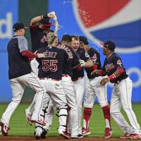 Cleveland’s Jay Bruce (center) is mobbed by teammates after driving in the winning run with a double in the bottom of the 10th inning against Kansas City on Thursday night. Indians stretch epic streak to 22