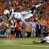 Los Angeles Chargers running back Melvin Gordon dives over Denver’s Justin Simmons for a touchdown in the first half on Monday night. Broncos block late FG, top Chargers