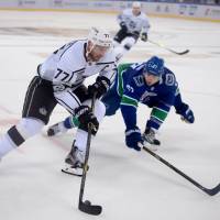 The Kings’ Jeff Carter controls the puck as the Canucks’ Ben Hutton defends in a preseason game in Beijing on Saturday. Los Angeles defeated Vancouver 4-3 after a shootout. Kings sweep Canucks in two-game exhibition series in China