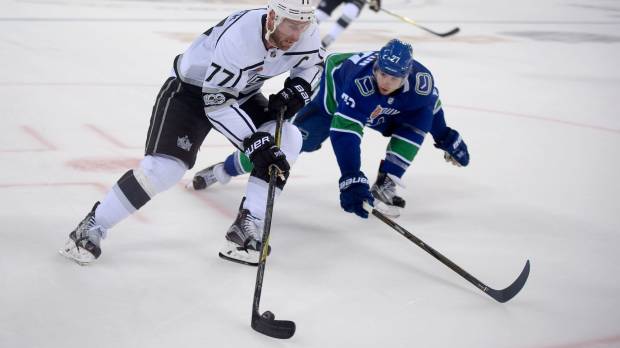 The Kings’ Jeff Carter controls the puck as the Canucks’ Ben Hutton defends in a preseason game in Beijing on Saturday. Los Angeles defeated Vancouver 4-3 after a shootout. Kings sweep Canucks in two-game exhibition series in China