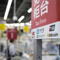 The bitcoin logo is seen at the information desk of the Bic Camera Akiba electronics store run by Bic Camera Inc. in Tokyo’s Akihabara district in June. More Chinese bitcoin operators are looking to run businesses in Japan because China’s authorities have tightened regulations. China's bitcoin barons seek new life in Japan and Hong Kong