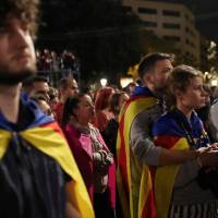 People react as they listen to Catalan President Carles Puigdemont during a gathering at Plaza Catalunya after voting ended for the banned independence referendum, Sunday in Barcelona, Spain. Unions, Catalan associations call for regional Tuesday strike in wake of referendum crackdown