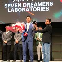 Seven Dreamers Laboratories Inc. CEO Shin Sakane (left) receives a trophy from Fenox Venture Capital CEO Anis Uzzaman after winning Japan’s preliminary round of the Startup World Cup on Wednesday. Laundry-folding robot maker will represent Japan at startup competition