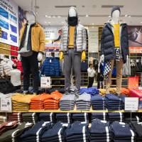 Jackets are displayed on mannequins at a Uniqlo store in the Orchard Central shopping mall in Singapore on Tuesday. As domestic market contracts, Uniqlo and 7-Eleven looks to make profits overseas