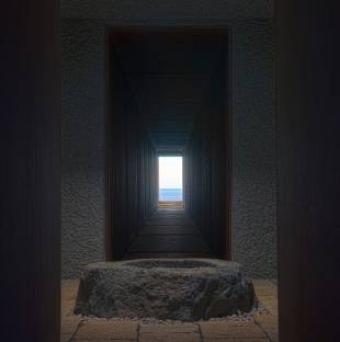 The interor of a steel chamber overlooking the ocean has a well at its center.