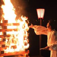 A priest throws paper wishes into a bonfire at the Kanazawa Yuwaku Bonbori Festival, which is based on a fictional festival in P.A. Works’ “Hanasaku Iroha” Anime tourism invites overseas fans to join festivities