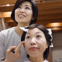 Maki Tsunoda, 56, receives makeup advice to conceal a skin disorder brought on by cancer treatment, during a visit to the Shiseido Life Quality Beauty Center in Tokyo's Ginza district on Oct. 27. | KYODO