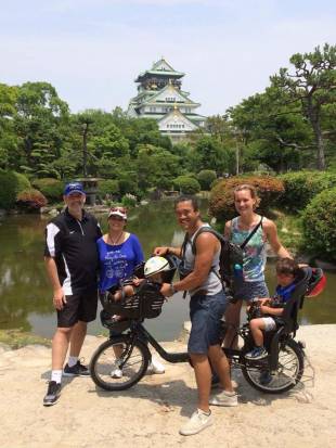 Cycle Osaka participants pose with an electric bike near Osaka Castle.