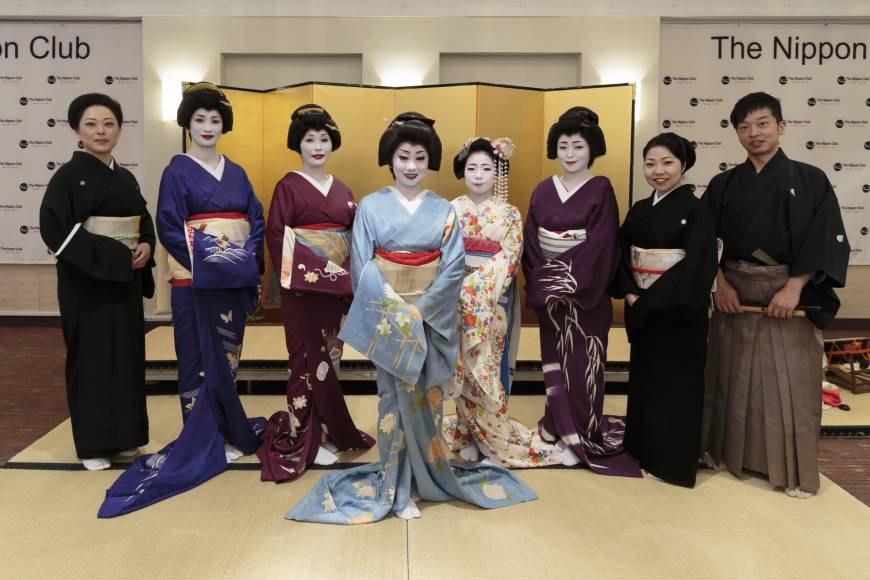 Kikuno (center), her maiko apprentice and three other geisha pose for a photo alongside members of the Hanaakari orchestra in New York.