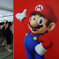 Travelers walk past a poster of Nintendo Co.’s Mario character at Terminal 1 of Kansai International Airport in Izumisano, Osaka Prefecture, in July. Nintendo opens games to rival console for first time with China-only Nvidia tie-up