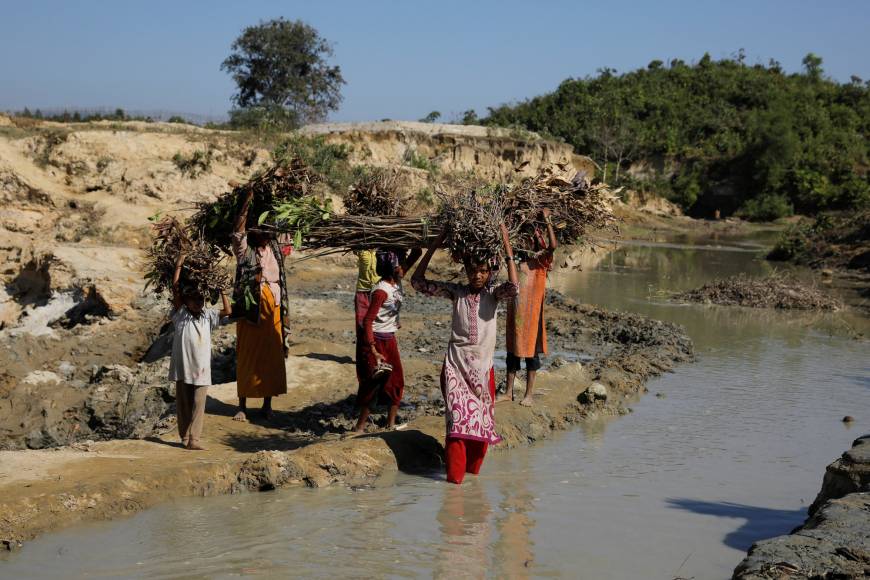 Sabura Khatun, a Rohingya refugee and her daughters carry firewood as they try to cross a stream near the Palongkhali refugee camp near Cox's Bazar, Banglades, Sunday. Three months ago, Sabura, a mother of six, arrived to Bangladesh from Myanmar's town of Maungdaw. Twice per week, while her husband waits with the youngest baby, Sabura and five of her daughters walk barefooted 4 km to a forest to bring firewood to cook rice. U.N. adopts resolution slamming Myanmar crackdown in Rohingya, defies opposition from China and Russia