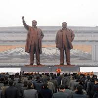 People place wreaths at the statutes of former North Korean leaders Kim Il-sung and Kim Jong-un in this photo released by North Korea’s Korean Central News Agency in Pyongyang on Dec. 24. A plan to acquire long-range cruise missiles capable of striking North Korea could set off heated debate in the Diet next year. Japan's defense buildup due to North Korea threat to come under scrutiny in 2018