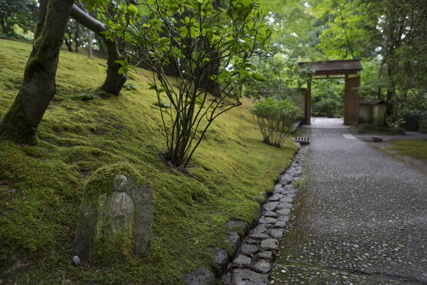 A moss-covered statue lies next to a path in the Portland Japanese Garden.