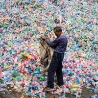 A Chinese laborer sorts plastic bottles for recycling in the village of Dong Xiao Kou, on the outskirts of Beijing, in September 2015. China's waste import ban upends global recycling industry