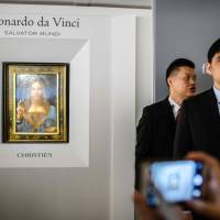 This picture taken in October shows a man (right) wearing blue tie identified by local Hong Kong media as former CIA agent Jerry Chun Shing Lee standing in front of a member of security at the unveiling of Leonardo da Vinci’s ‘Salvator Mundi’ painting at the Christie’s showroom in Hong Kong. Arrested ex-CIA agent linked to dozen U.S. spy deaths was Christie's security guard in Hong Kong