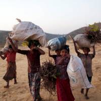 Rohingya refugee children smile for the camera as they carry firewood at Palong Khali refugee camp near Cox’s Bazar, Bangladesh, on Tuesday. Myanmar admission that soldiers killed Rohingya 'an important step,' U.S. envoy says