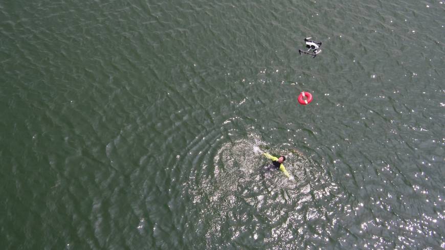 Officials from the Yaizu Crisis Management Division guide a drone that has been fitted with a life buoy to the location of a person in need of help in the ocean as part of an emergency drill.