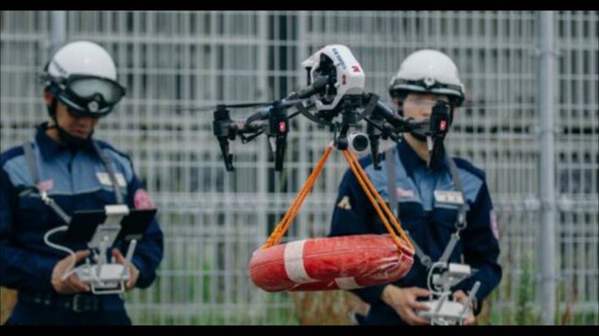 Officials from the Yaizu Crisis Management Division guide a drone that has been fitted with a life buoy to the location of a person in need of help in the ocean as part of an emergency drill.