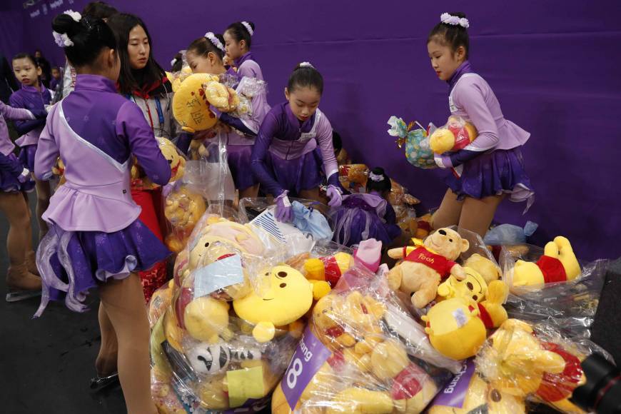 Olympic staff gather Pooh bears thrown by fans following the short program performance of Yuzuru Hanyu.