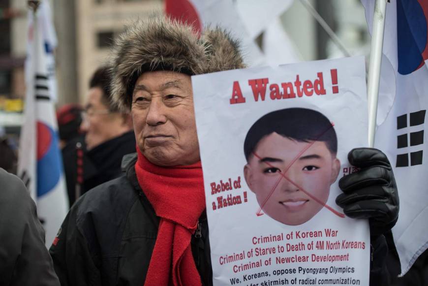 A South Korean protester holds a banner featuring the image of a mask worn by North Korean cheerleaders the previous day. The protestors accused South Korean President Moon Jae-in of allowing North Korea to stage its 