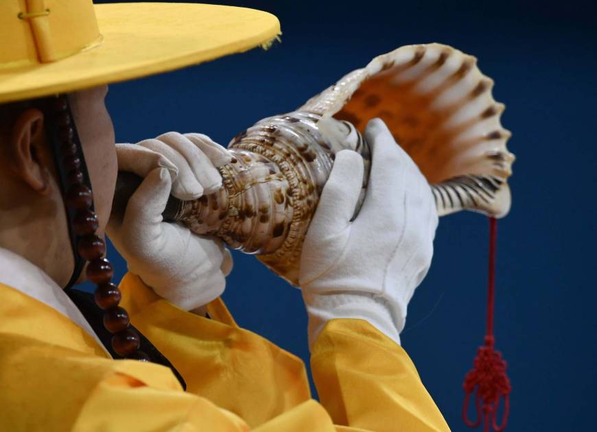 A man blows a conch during the ceremony before the start of the mixed doubles final in which Canada and Switzerland competed.