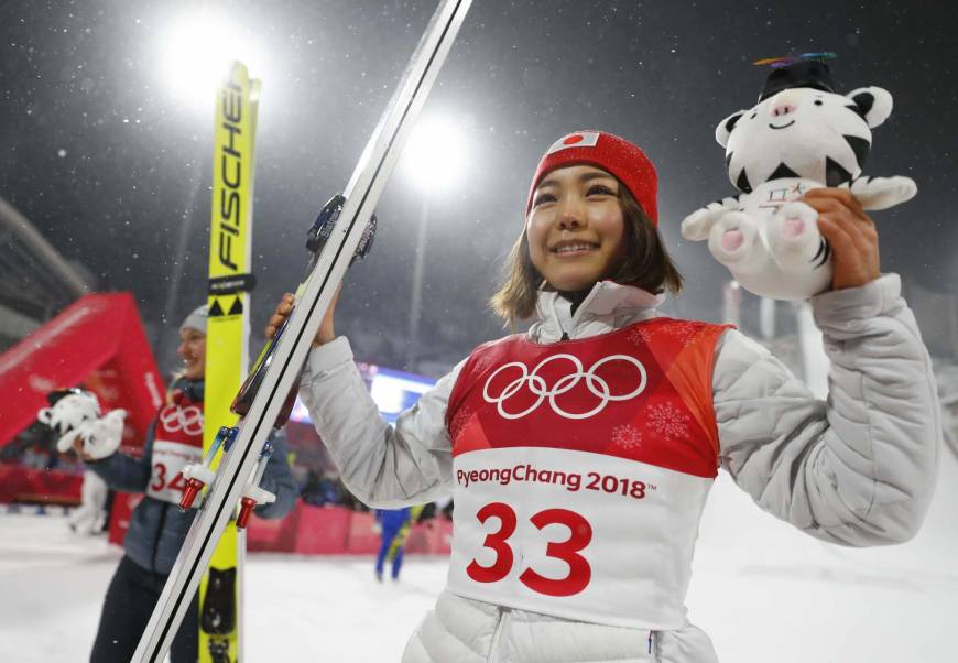 Bronze medalist Sara Takanashi celebrates on the podium alongside gold medalist Maren Lundby during the victory ceremony.