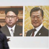 A woman walks past a public TV screen showing a news clip with the photos of North Korean leader Kim Jong Un (left) and South Korean President Moon Jae-in in Tokyo on Wednesday. Prospect of U.S.-North Korea summit prompts jitters in Tokyo about being left vulnerable
