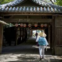 One down: A pilgrim, known as o-henro-san, walks through the gates of Ishiteji, temple number 51 of 88 on the Shikoku Pilgrimage. No right way to complete Shikoku's 88-temple pilgrimage