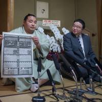 Kakuryu holds the banzuke rankings for the first time as a yokozuna as his stablemater Izutsu watches on April 24, 2014. Quiet man Kakuryu on top after long struggle