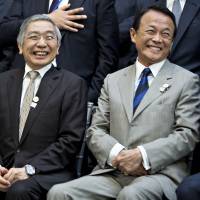 Finance Minister Taro Aso (right) and Bank of Japan Gov. Haruhiko Kuroda laugh while attending a Group of 20 finance ministers and central bank chiefs group photo on the sidelines of the spring meetings of the International Monetary Fund (IMF) and World Bank in Washington on Friday. G-20 finance chiefs wary of trade friction but short on solutions