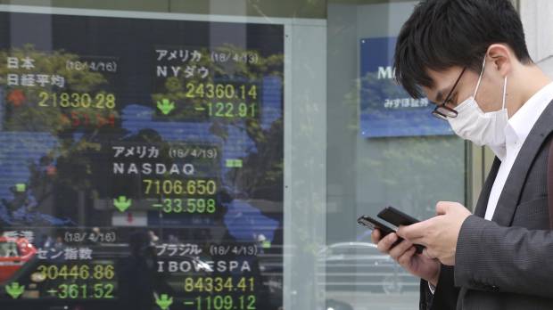 A man walks by an electronic stock board at a securities firm in Tokyo on Monday. Nomura says Abe scandal and trade risk could erupt for Japan stocks