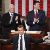 French President Emmanuel Macron gestures as he is introduced before speaking to a joint meeting of Congress in Washington on Wednesday. Standing behind him are Vice President Mike Pence and House Speaker Paul Ryan. Macron resists Trump's 'America first' in speech to Congress