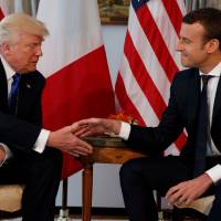 U.S. President Donald Trump (left) shakes hands with French President Emmanuel Macron during a meeting at the U.S. Embassy in Brussels last May. Macron arrives Monday in Washington for the first state visit of Trump’s presidency. The two men have an unlikely friendship, despite strong differences on areas such as climate change. French globalist Macron maintains tough-love friendship with nationalist Trump