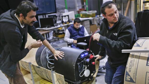 Nikhil Jog (center) works on a computer as Mohammad Mousaei (left) and David Kohandash work on the RadPiper robot in the robotics institute at Carnegie-Mellon University in Pittsburgh on April 4. Robot designed for faster, safer pipe cleanup at U.S. Cold War-era uranium plant