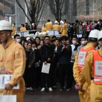 Neighborhood residents and workers take part in a disaster drill March 9 at the Roppongi Hills shopping complex in Minato Ward, Tokyo. Japan's vaunted quake and missile alert system runs up against limits