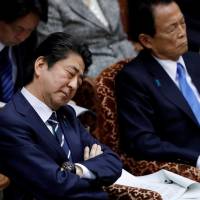 Prime Minister Shinzo Abe, flanked by Finance Minister Taro Aso (right), attends a Diet session in the Upper House on March 28. On sex harassment complaint, Finance Minister Taro Aso objects to font size