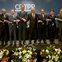 Trans-Pacific Partnership Minister Toshimitsu Motegi (fourth from right) and officials from 10 other nations join hands after the signing ceremony for the CPTPP in Santiago on March 8. Japan played a leading role in forging the TPP 11 deal. Japan's multilayered, multilateral strategy