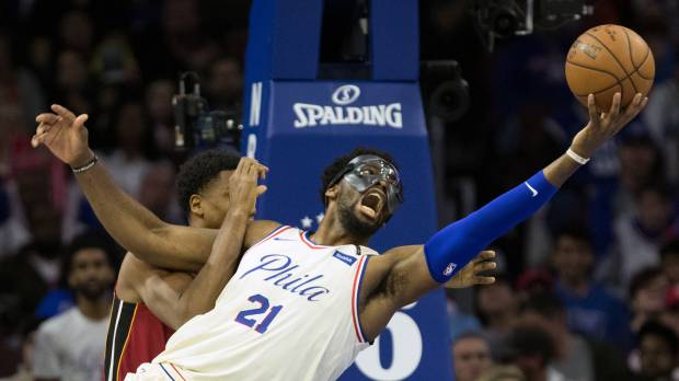 Philadelphia’s Joel Embiid (right) is fouled by Miami’s Hassan Whiteside during the 76ers’ 104-91 win over the Heat on Tuesday. Sixers put Heat on ice with victory in Game 5