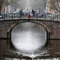 Cyclists cross a bridge in central Amsterdam last December. New Amsterdam government determined to tame tourism with restrictions on Airbnb and 'beer bikes'