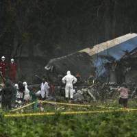 Rescue teams search through the wreckage site of a Boeing 737 that plummeted into a cassava field with more than 100 passengers on board, in Havana on Friday. The Cuban airliner crashed just after takeoff from Havana’s international airport in the Cuban capital. Airliner with 110 aboard crashes in Cuba; three said to survive