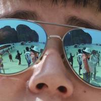Tourists are reflected in sunglasses on Maya Bay on Phi Phi island in Krabi province, Thailand, on Thursday. Thailand's Maya Bay, made famous by film 'The Beach,' set to close to tourism for four months