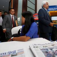 The Phnom Penh Post’s new owner, Sivakumar Ganapathy (right), leaves after a news conference in Phnom Penh, Cambodia, on Friday. New Phnom Penh Post owner defends 'rocky start' amid concerns over press freedom