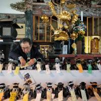 Broken-down Aibos, Sony Corp.’s famed first-generation pet robot, are arranged on an altar prior to their “funeral” at Kofukuji Temple in Isumi, Chiba Prefecture, last Thursday. In Japan, Aibo robots get their own funeral